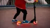 A child is riding a scooter with illuminated wheels on a paved path. Náhľad obrázku produktu
