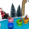 A miniature Christmas scene with Santa, trees, and children in colorful cups on a blue ice rink. Náhled obrázku produktu