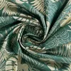A close-up view of a green fabric with a gold monstera leaf pattern, folded and draped. Produktbild-Vorschau