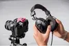 A person is holding headphones next to a camera with a pink accessory attached. Náhľad obrázku produktu