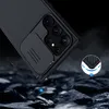 A black phone case with a sliding camera cover is shown at an angle, with a close-up inset showing the corner protection. The background is dark and rocky, with some abstract blue glowing elements. Anteprima dell’immagine prodotto