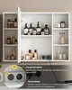 A white bathroom cabinet with its door open, displaying various toiletries and accessories. A close-up inset shows electrical outlets and controls. Voir les images du produit