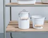 Two white enamelware containers, a milk can and a bucket, sit on a wooden shelf. Produktbild-Vorschau