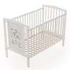 A white baby crib with a wooden slatted base and a decorative panel featuring two teddy bears, a star, a heart, and a moon. Náhľad obrázku produktu