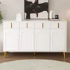A white sideboard with gold handles and legs, placed in a room with a painting on the wall and a rug on the floor. Produktbild-Vorschau