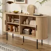 A modern wooden sideboard with various decorative items and storage baskets, placed in a well-lit room with a rug on the floor. Anteprima dell’immagine prodotto