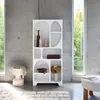 A white, organically shaped bookshelf filled with decorative items, placed in a modern room with concrete walls and large windows. Produktbild-Vorschau