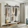 A room with a wall-mounted garment rack displaying clothes and accessories, with curtains and a sofa visible in the background. Produktbild-Vorschau