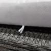 A close-up view of the texture of a gray rattan weave and a gray cushion with a white tag attached. Podgląd zdjęcia produktu