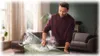 A man is ironing clothes in a living room. Voir les images du produit