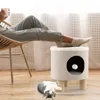 A person relaxing in a chair with their feet up on a cat tree, while a cat lies on the floor nearby. Voir les images du produit