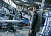 A man is operating a miter saw in a workshop. Voir les images du produit
