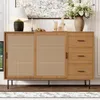 A wooden sideboard with cane doors and three drawers, displayed in a well-lit room with decorative items on top. Voir les images du produit