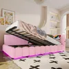 A pink upholstered bed with the mattress lifted to reveal storage space, in a bedroom setting with artwork on the wall and shelves in the background. Náhled obrázku produktu