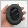 A hand holding a black headphone earpad. Produktbild-Vorschau