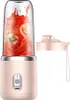 A pink portable smoothie maker with a clear blending cup filled with tomatoes and juice, shown next to its pink lid. Produktbild-Vorschau