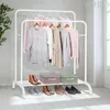 A white metal garment rack with clothes hanging on it and storage boxes and shoes on the shelves below. Podgląd zdjęcia produktu