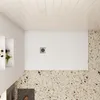 A top-down view of a white shower tray with a silver drain cover, set against a speckled floor and a tiled ceiling. Produktbild-Vorschau