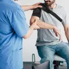 A physical therapist adjusts a shoulder brace on a patient. Anteprima dell’immagine prodotto