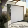 A modern outdoor space with a large white screen deployed from a building structure, likely a vertical awning or screen. Náhled obrázku produktu
