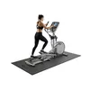 A woman is using an elliptical machine on a mat. Anteprima dell’immagine prodotto