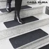 A person wearing black boots walks down a set of stairs with dark gray stair mats. Produktbild-Vorschau