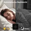 A split image showing a woman sleeping in bed during the day on the left, and the same scene at night on the right, with a small camera in the foreground. Produktbild-Vorschau