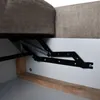 A close-up view of the internal mechanism of a sofa, showing a spring and metal support structure. Produktbild-Vorschau