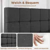 A close-up of a dark gray upholstered bed frame with text overlays highlighting features, and a separate inset showing a hand pressing into a white foam mattress. Produktbild-Vorschau