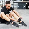 A man is sitting on the ground and putting on ankle weights. Produktbild-Vorschau