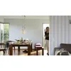 A woman walks through a doorway into a dining room with a table set for a meal. Produktbild-Vorschau