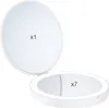 A white makeup mirror with two sides, one with normal magnification and the other with 7x magnification, is shown open against a white background. Produktbild-Vorschau