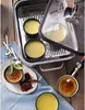 A WMF Aroma Steamer Vitalis with silicone band, 6.5 L, made of stainless steel, is shown with several crème brûlée desserts prepared in it. Some desserts are in the steamer, while others are on a plate and being torched. Náhľad obrázku produktu