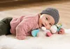 A baby lying on a fluffy rug, playing with a stuffed donkey toy. Podgląd zdjęcia produktu