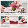 A close-up of a person using a pink vegetable slicer with a cucumber. Produktbild-Vorschau
