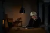 A person is reading a book at a table under a pendant lamp. Produktbild-Vorschau
