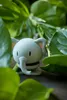 A small, light gray elephant figurine is nestled among lush green leaves. Produktbild-Vorschau