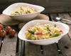 Two white pasta bowls filled with pasta, asparagus, and cherry tomatoes, placed on a rustic wooden table with some cherry tomatoes and cutlery in the background. Voir les images du produit