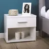 A white nightstand next to a bed, decorated with a framed photo and a basket. Produktbild-Vorschau