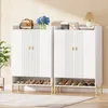 Two white shoe cabinets with gold accents are shown side-by-side, with shoes displayed on the open shelves below. Decorative items are placed on top of the cabinets. Náhľad obrázku produktu