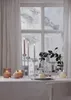 A table set for a cozy evening with lit candles and a window view of a snowy landscape. Produktbild-Vorschau