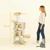 A woman and a cat stand next to a beige cat tree with dimensions labeled. Náhled obrázku produktu