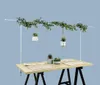 A table set for a meal with decorative plants and a hanging garland. Produktbild-Vorschau