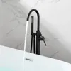 A black freestanding bathtub faucet with water running into a white bathtub. Produktbild-Vorschau