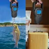 A split image showing a portable scale being used to weigh a fish on one side and a suitcase on the other. Produktbild-Vorschau