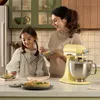 A woman and a child are in a kitchen, preparing or enjoying tarts. Produktbild-Vorschau