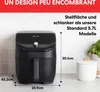 An air fryer is shown on a kitchen counter with dimensions indicated. Produktbild-Vorschau
