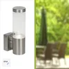 A product image split into two halves. The left half shows a stainless steel outdoor wall light with a clear glass cylinder. The right half shows a blurred outdoor seating area with chairs and an umbrella. Produktbild-Vorschau