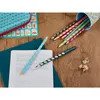 Colored pencils are arranged on a wooden surface next to a notebook with handwriting practice. Anteprima dell’immagine prodotto
