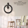 A decorative gear-shaped wall clock is displayed on a wall above a wooden stool with a teapot and cup, and a striped armchair. Voir les images du produit